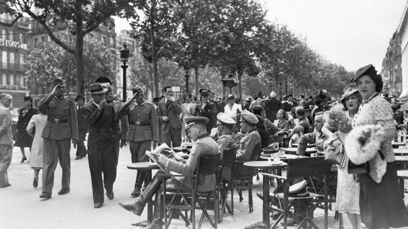 Black and white photo of German soldiers and French civilians sitting in open air cafes in Paris.