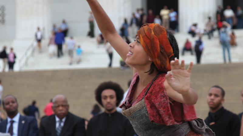 Color photo of an African-American interpretive dancer performing on the steps of the Lincoln Memorial.