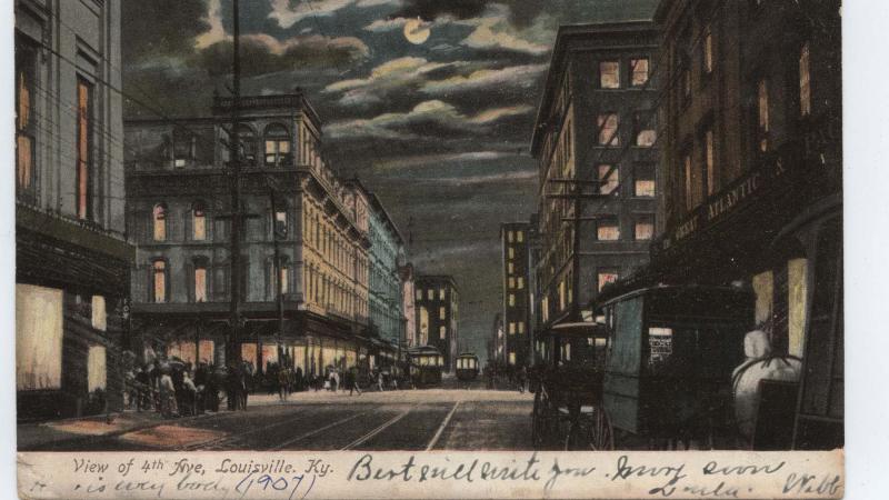 Night view of fourth avenue, with a full moon shining in a cloudy sky, lights on in the buildings