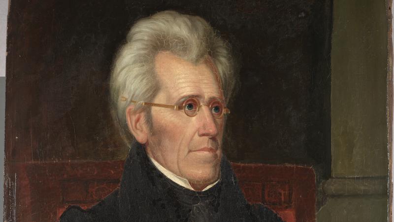 Jackson, wearing small, round eyeglasses, gray hair combed back, body turned slightly to his left, away from the painter