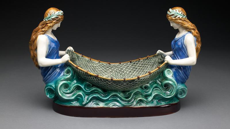 Image of a painted ceramic sculpture of two women tending a net between them.