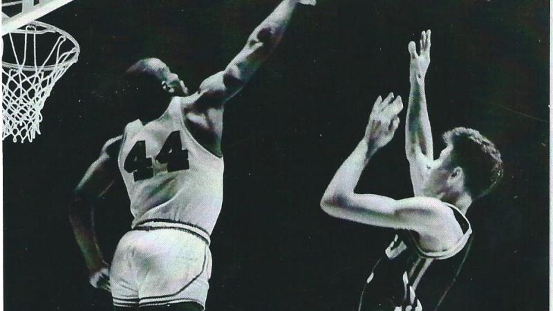 Flick shoots the basketball midjump, as Currie tries to block his shot with an outstretched arm