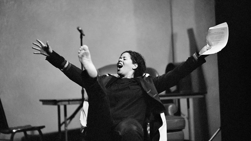 Black and white photo of Anna Deavere Smith acting on stage and making an exclamation.