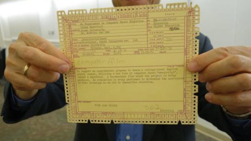 A man holding a yellow McBee punch card up close to the camera.