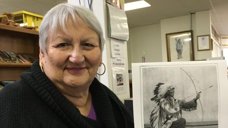 Photo of a woman holding a photo of a Native American man holding a bow