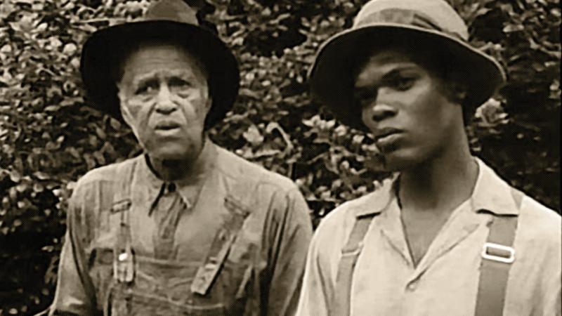 black and white film still of two men in farming clothes