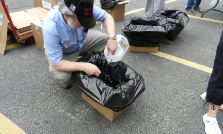 A man crouching over a cardboard box, where he is inserting the negative of a photograph