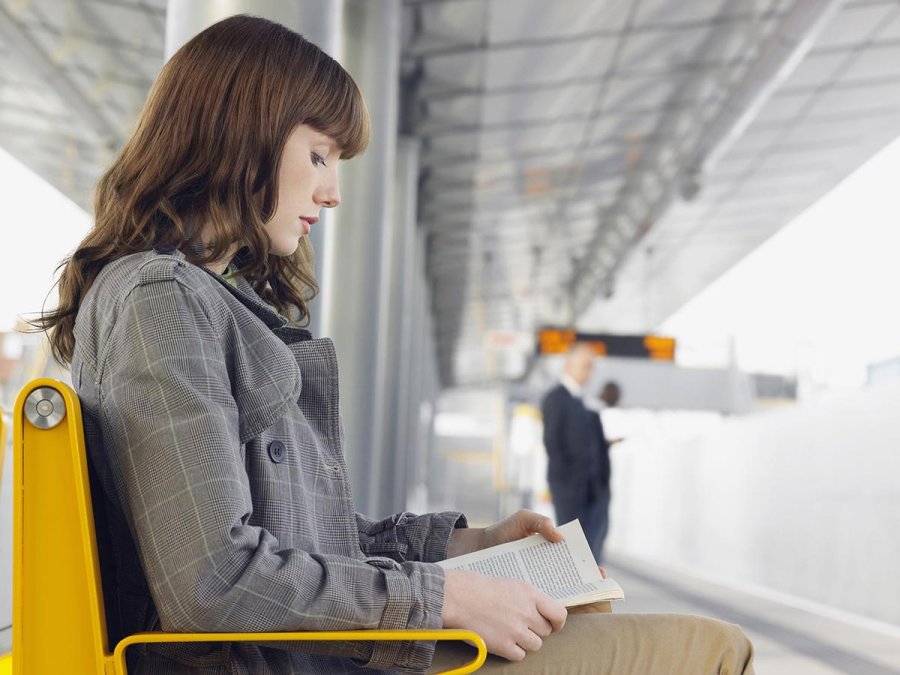 Dreamstime.com / Businesswoman Reading Book At Train Station Photo