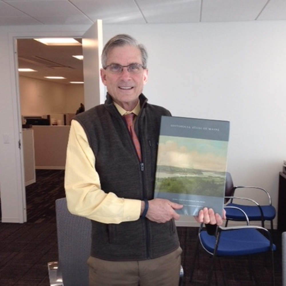 NEH Chairman William "Bro" Adams holding the Historical Atlas of Maine.