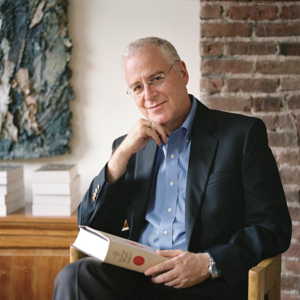 Ron Chernow, seated, with a book in his lap