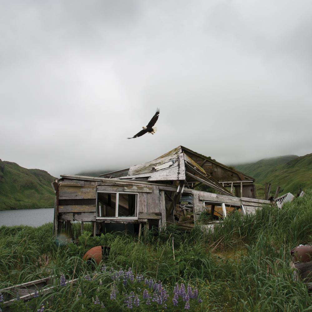 Photograph of cloudy sky in background, destroyed house in foreground