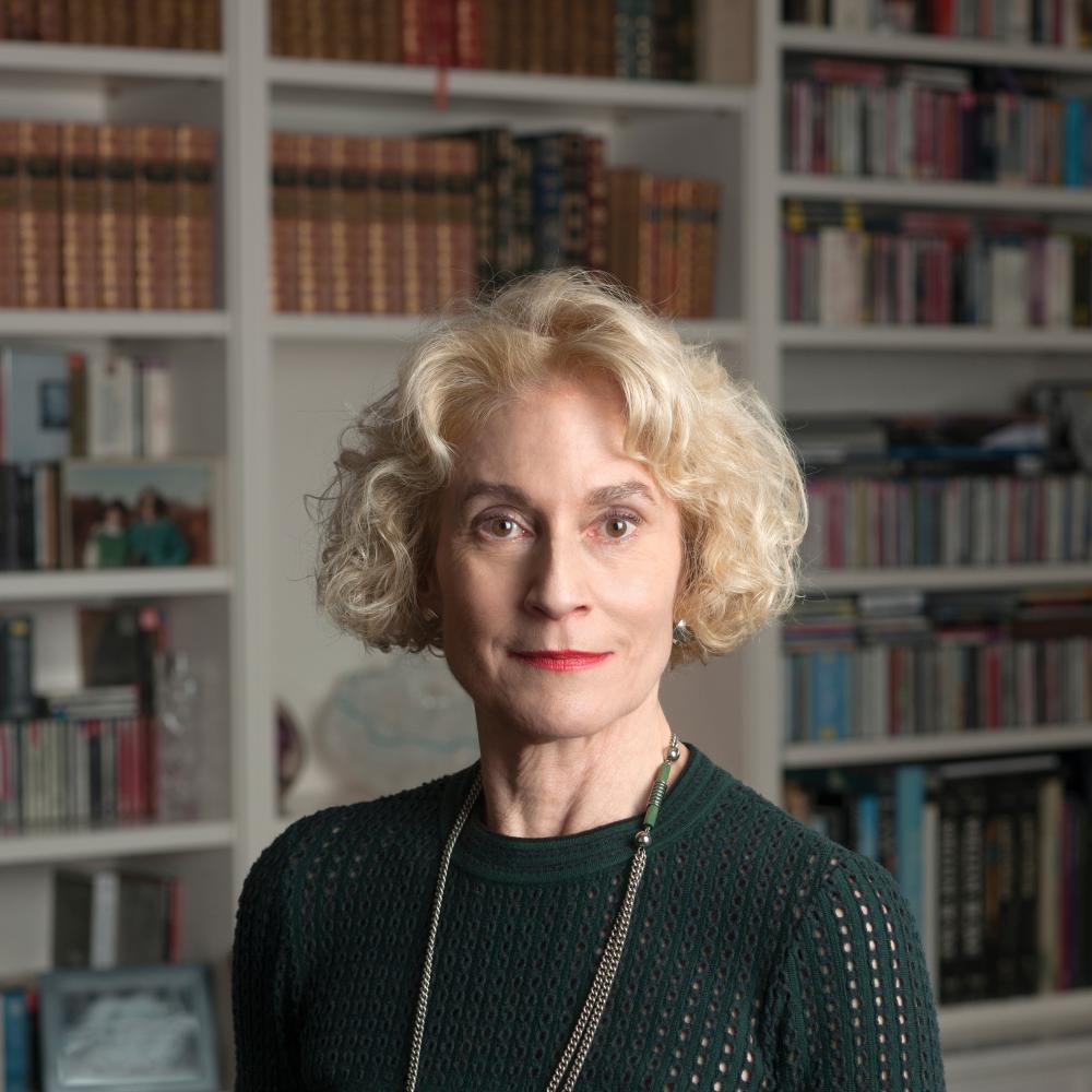 A portrait photo of Martha Nussbaum standing in front of a large bookcase. 