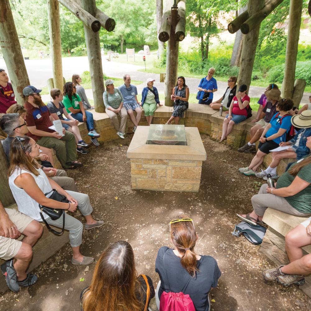 Visitors listen to a guide during a tour of the bdote sites