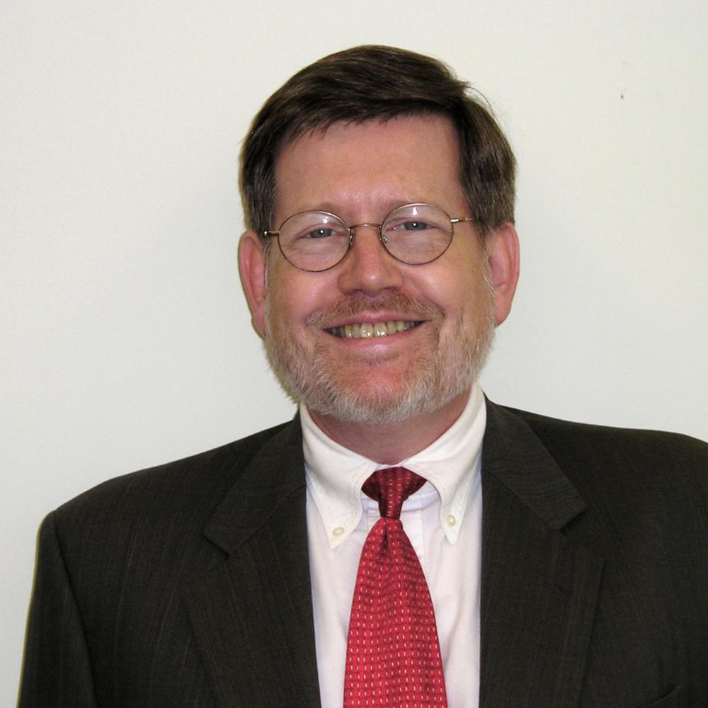 headshot of Robert Bailey, wearing glasses, a black suit and red tie