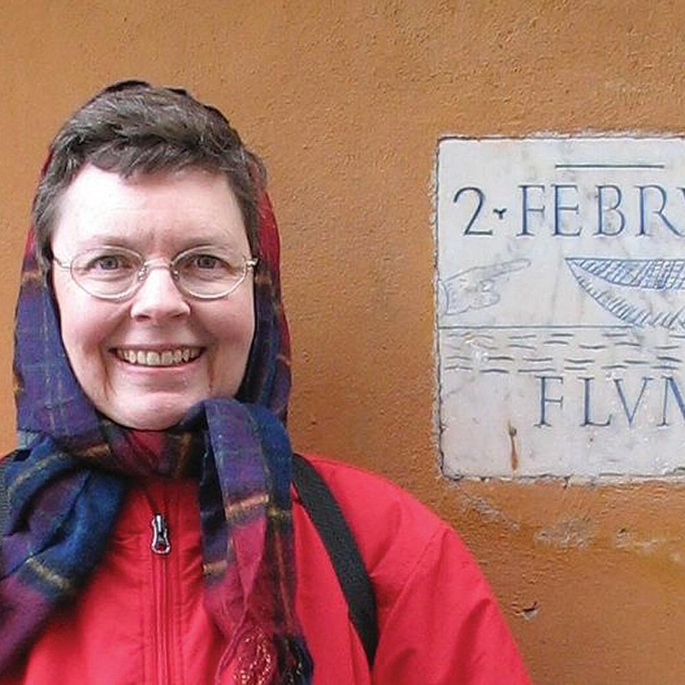 photograph of woman standing in front of a plaque