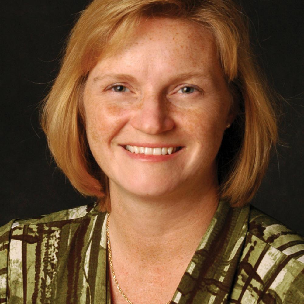 Rippy, auburn hair cut to her shoulders, in a green and brown striped blouse