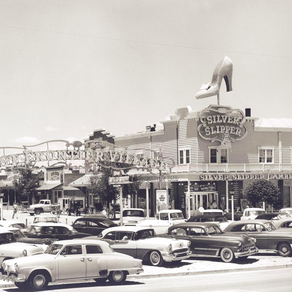 black and white photo of a parking lot, building in background