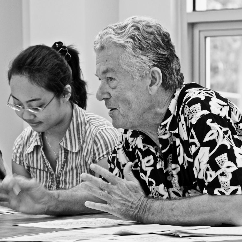 black and white photograph of a man excitedly talking at a table, a woman sits next to him