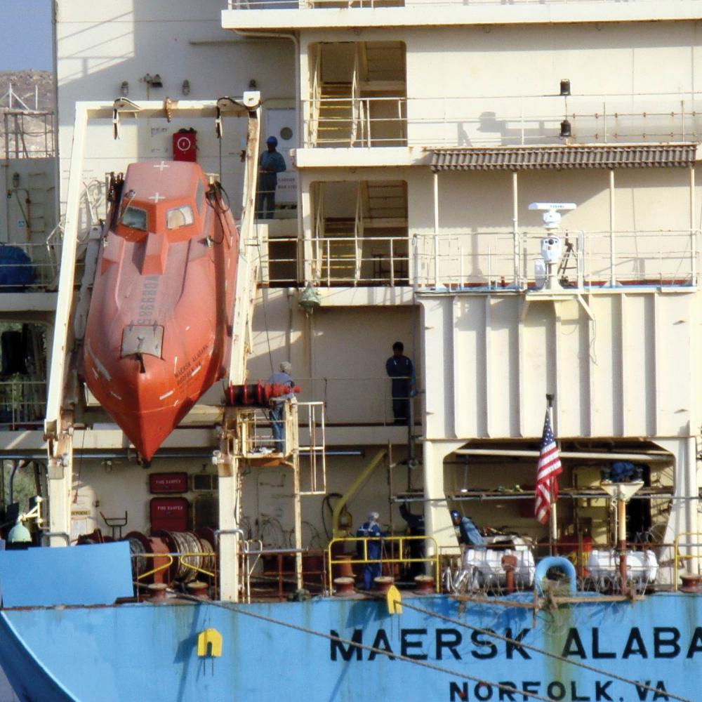 Photograph of a boat lowering a submarine into water