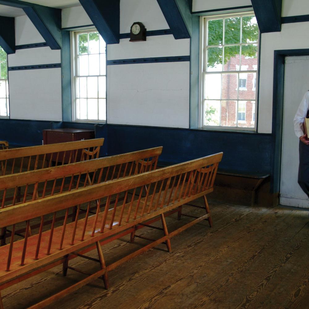 man entering an empty room filled with pews