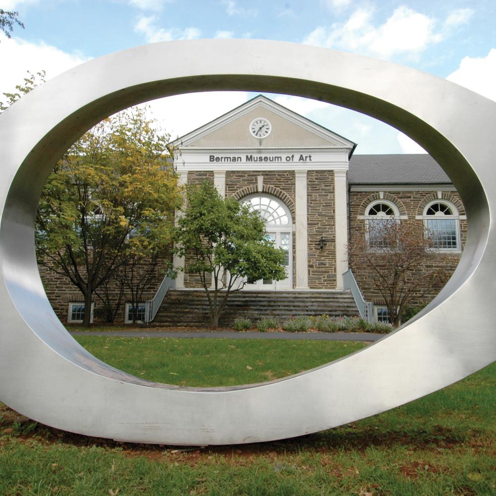 An artistic sculpture in an oval shape made of stainless steel before the Berman Museum of Art at Ursinus College.