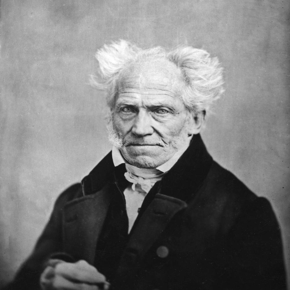 Schopenhauer in a dark suit and white shirt, with fluffy white hair fringing a bald head