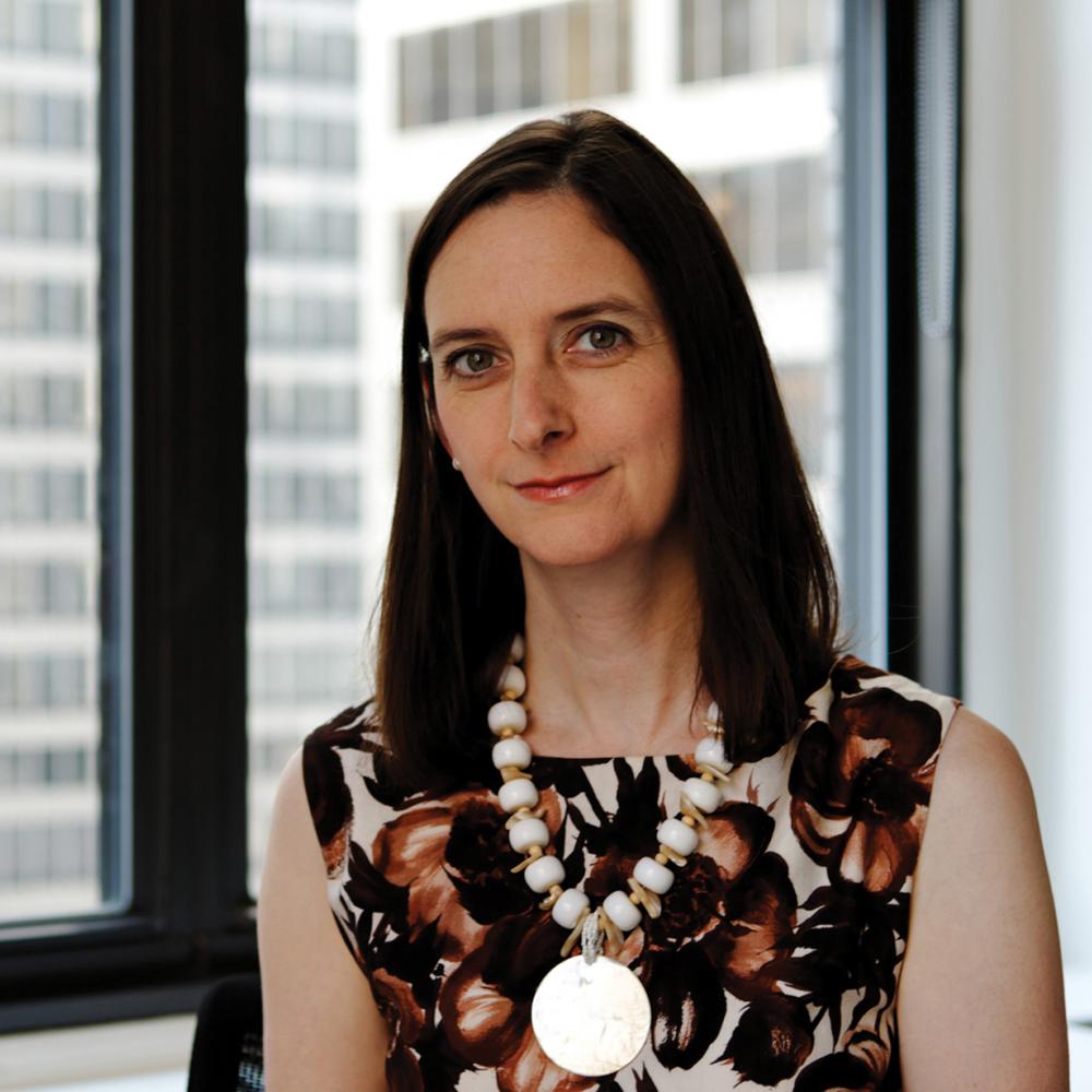 Color photo of Sara Ogger wearing a large necklace and leaf-patterned dress.