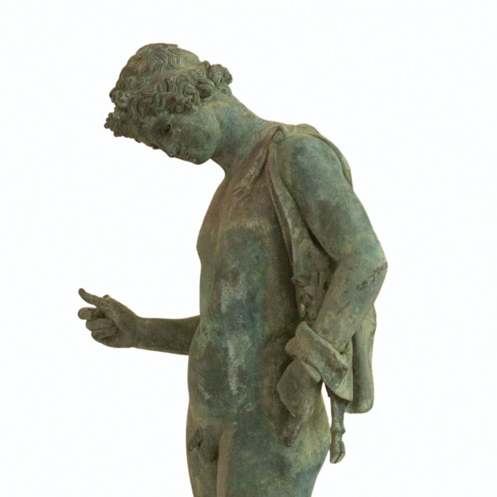 A bronze statue standing in a contemplative pose.