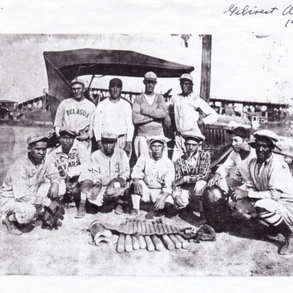 Black and white photo of a baseball team kneeling for a portrait.