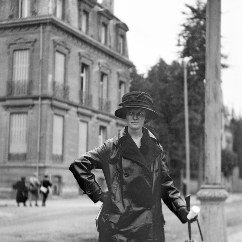 Black and white photo of a woman in an elegant raincoat and hat.