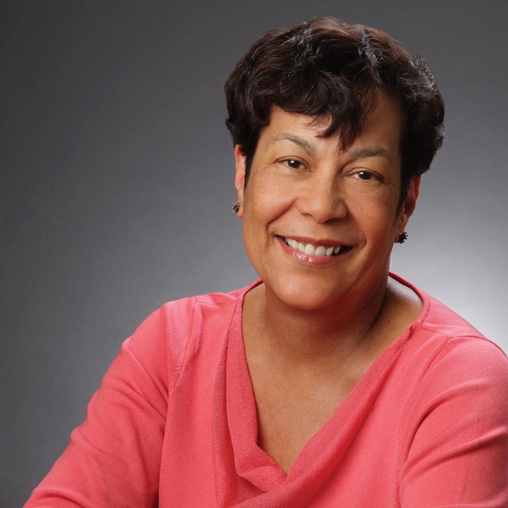 Color photo portrait of Carla Peterson in a pink blouse, with short hair.