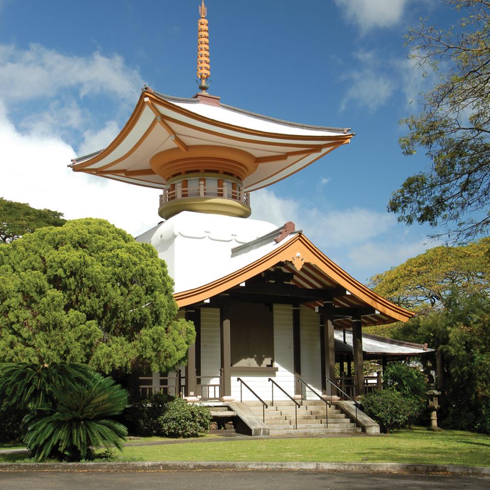 Color photo of a temple with a pagoda amid lush trees.