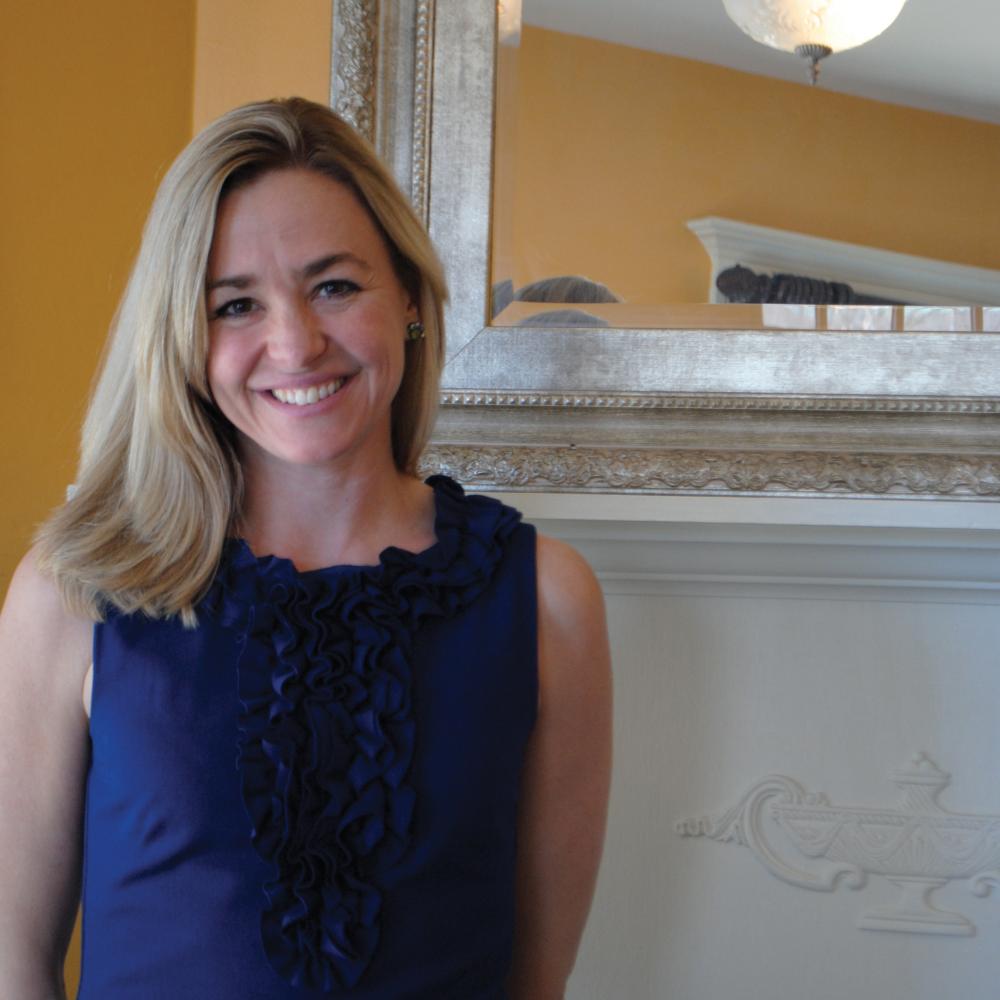 Color photo of Keira Amstutz standing with her hands folded behind her back, smiling.