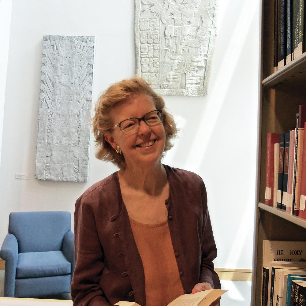 Color photo of Katherine Rinne standing with a book in her hands.