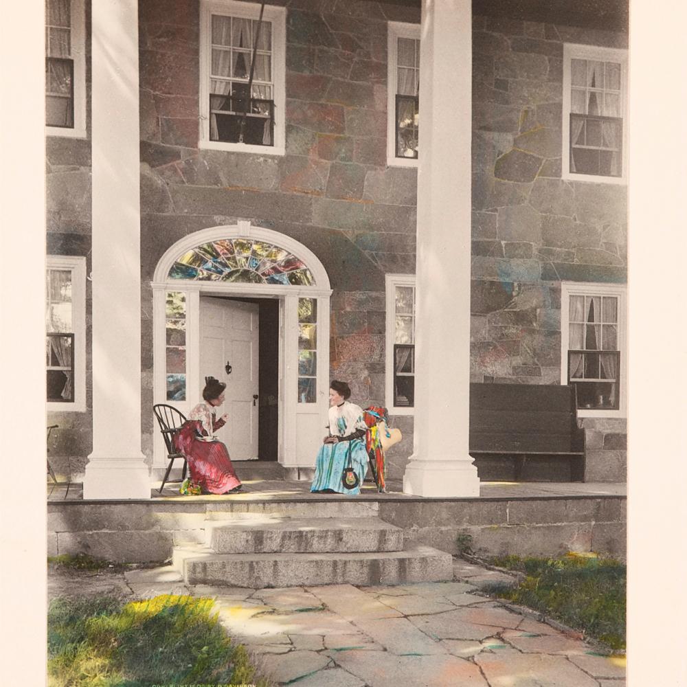 Color illustration of two old ladies conversing on the porch of a large house with front columns.