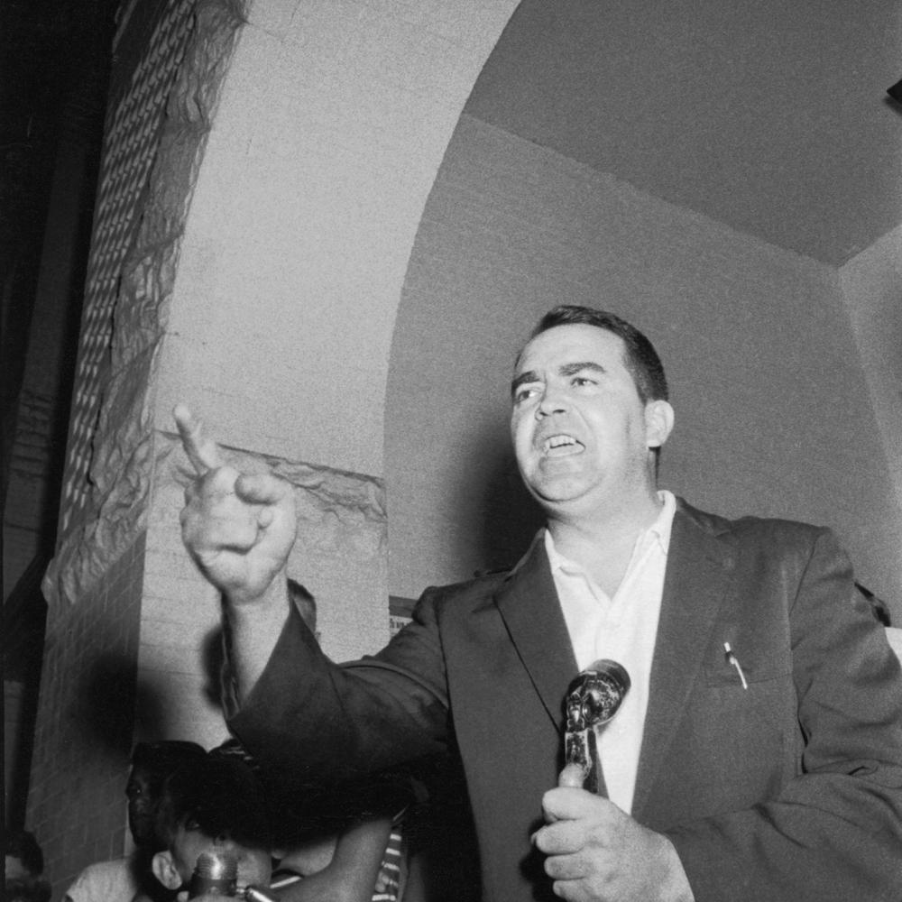 Black and white photo of Asa Carter giving an impassioned speech while gesturing with his finger.
