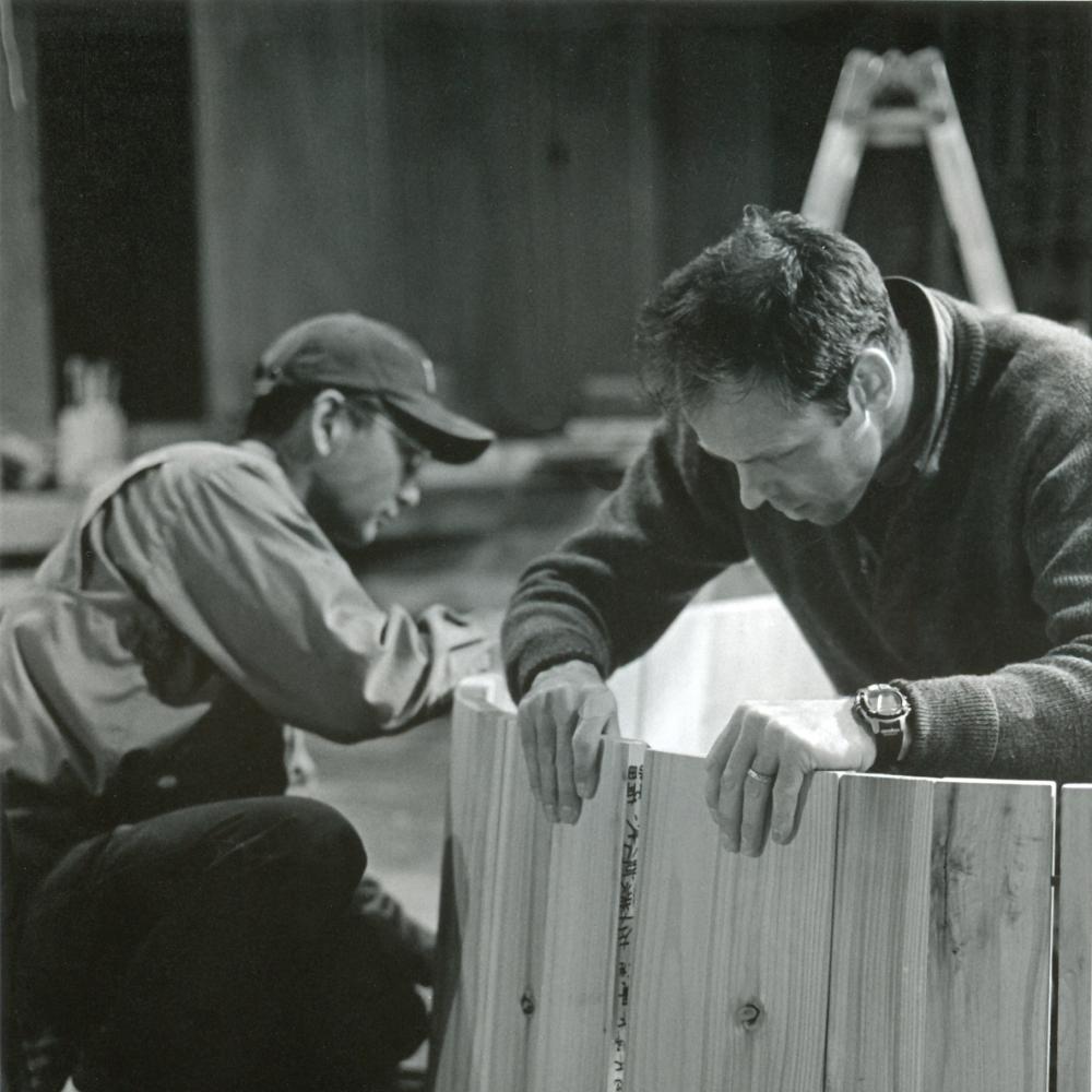 black and white photo of two men working on a piece of wood