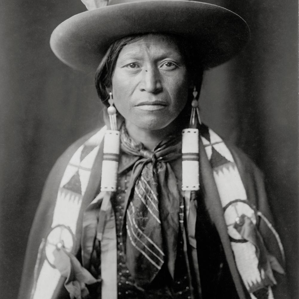 Black and white photo of apache cowboy in hat and scarf