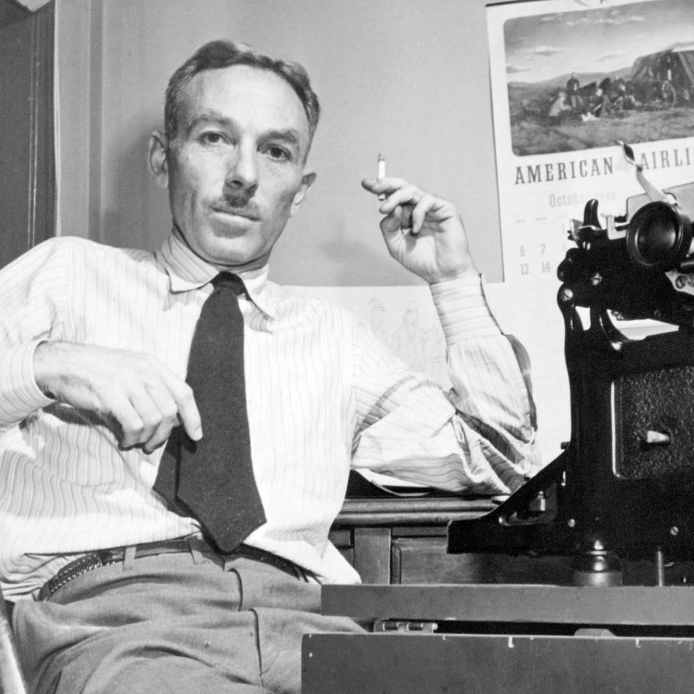 White smoking a cigarette and sitting in front of a typewriter