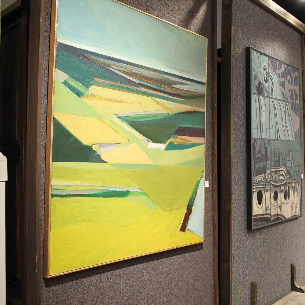 A gallery wall, at an angle, with three paintings: the one closest to the viewer painted in vivid greens and yellows, the other two are darker and cooler-toned