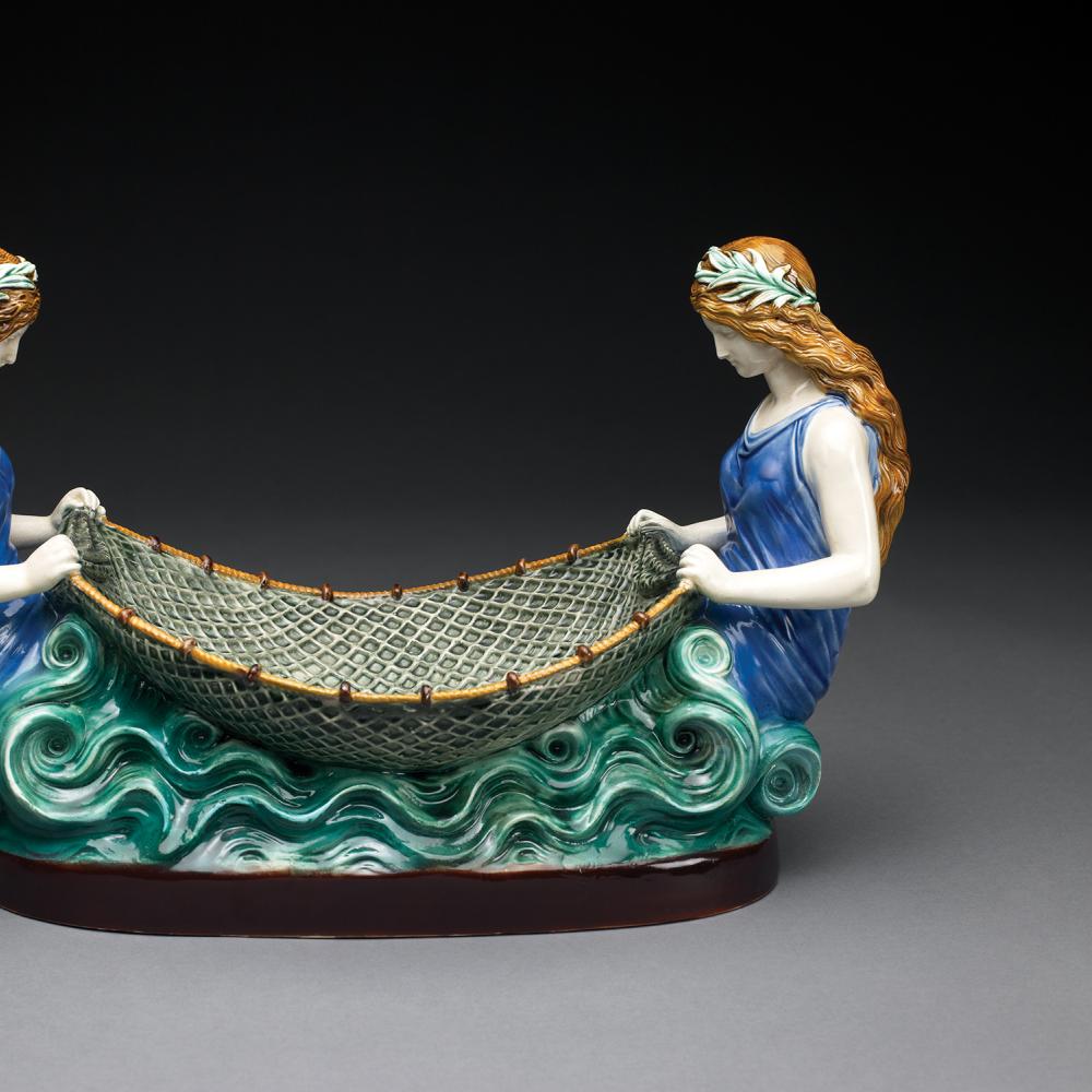 Image of a painted ceramic sculpture of two women tending a net between them.