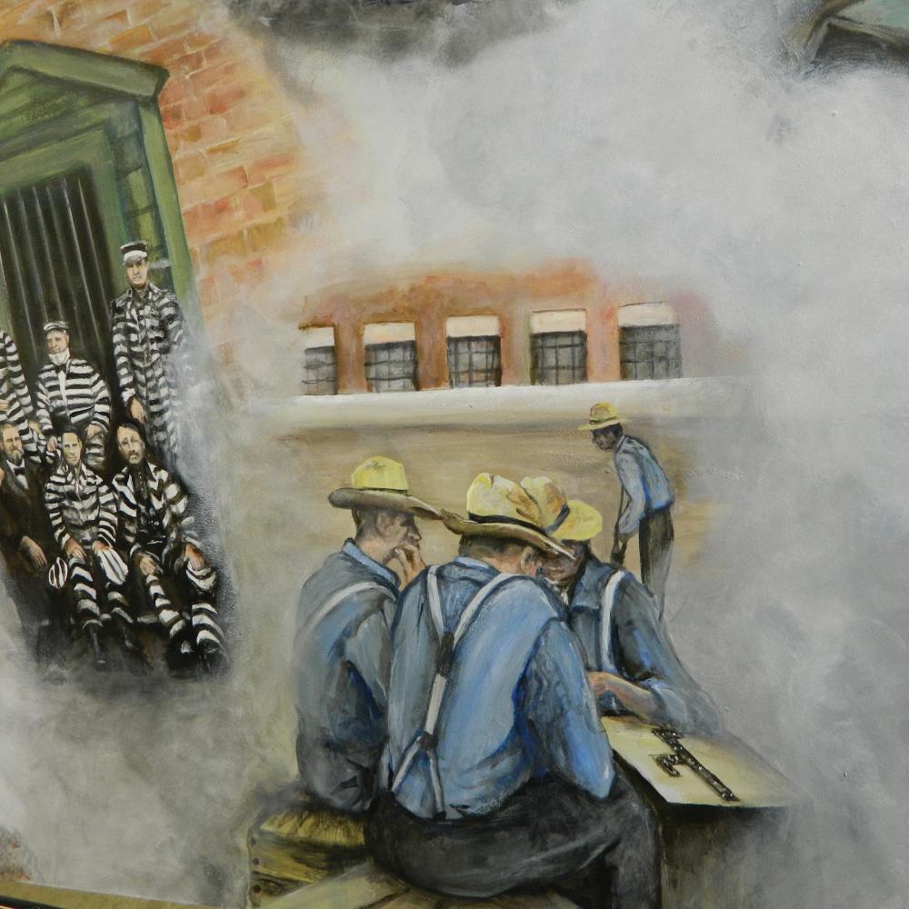 Mural showing prisoners in striped uniforms on the left, and a group of blue shirted men huddled around a table on the right