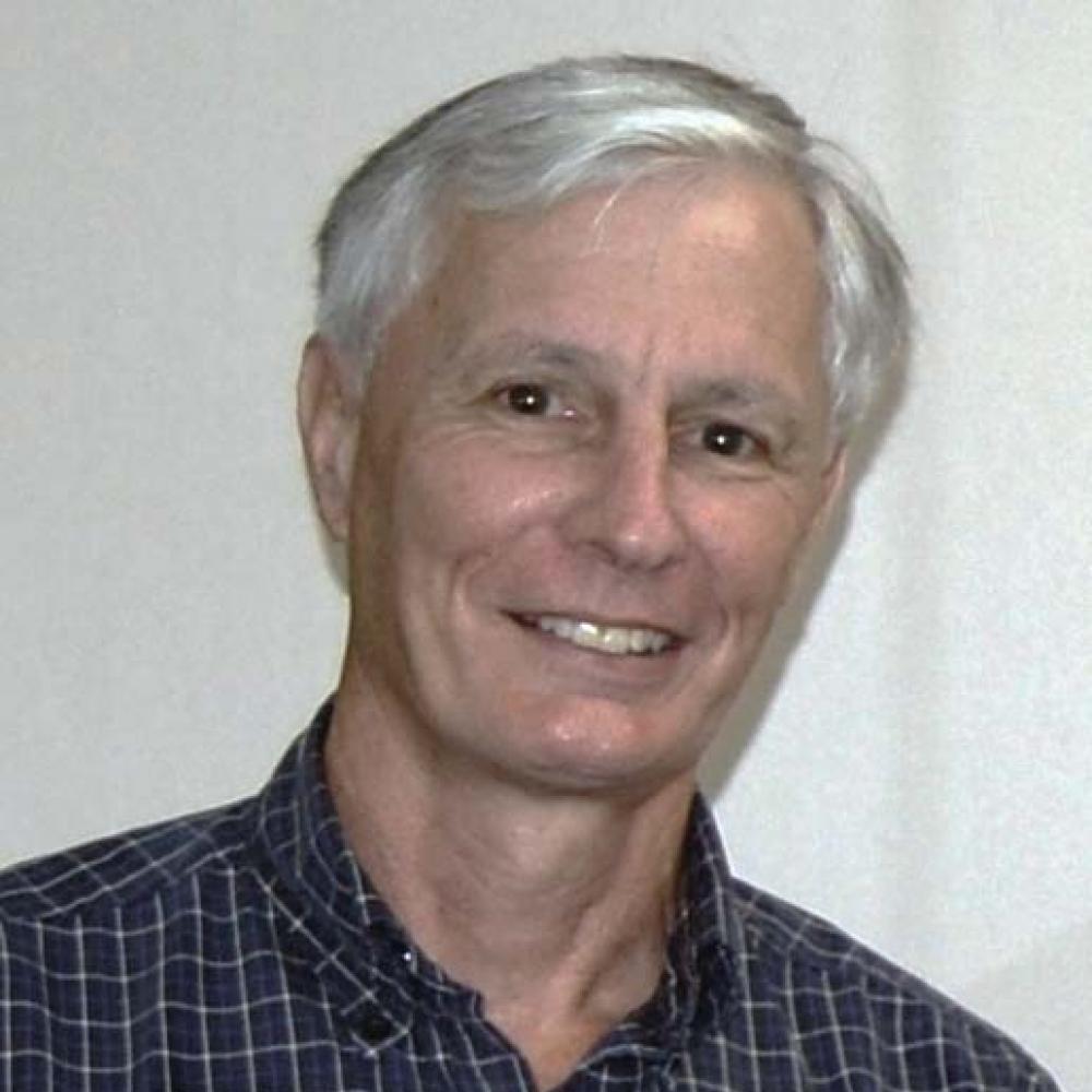 Russell, with white hair, wearing a black and white grid patterned shirt