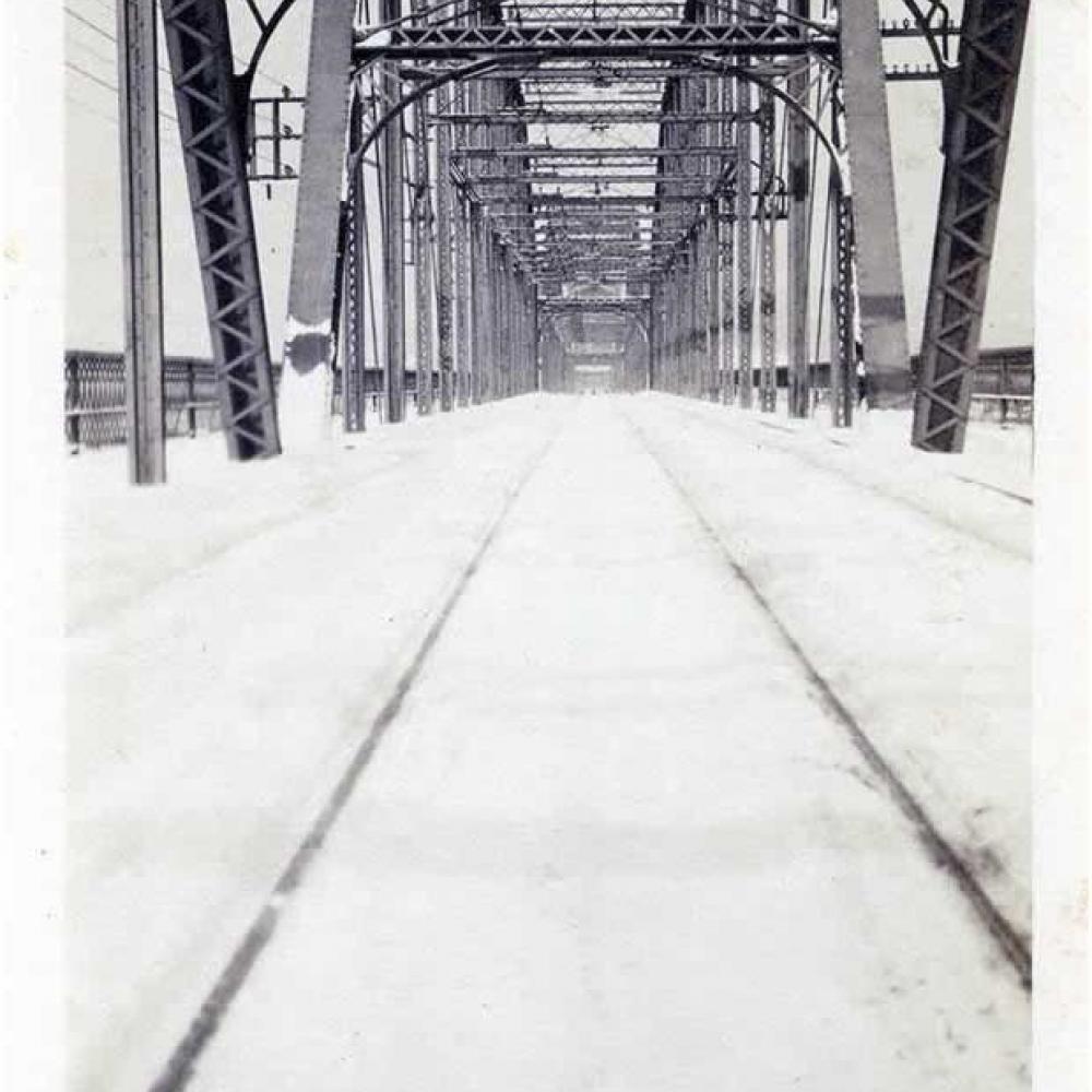 Black and white photo of a bridge, looking down it.