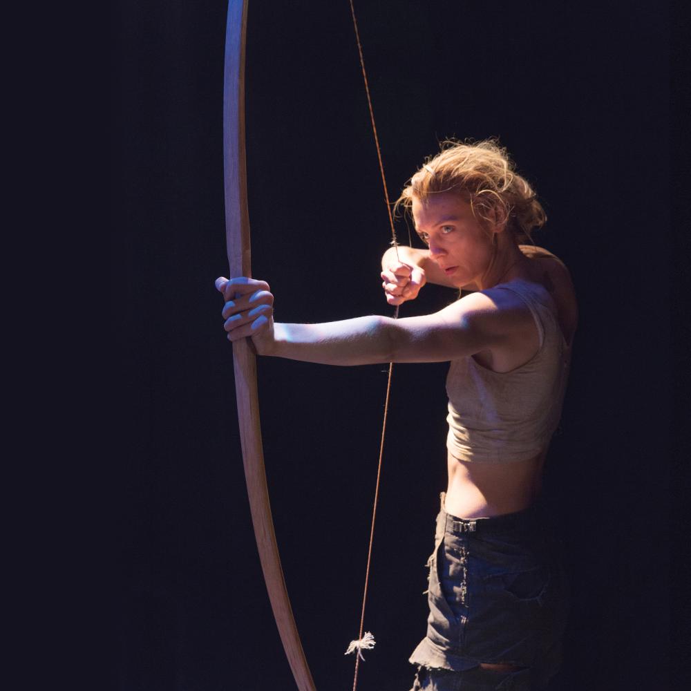 Color photo of a woman pulling an arrow back on her bow.