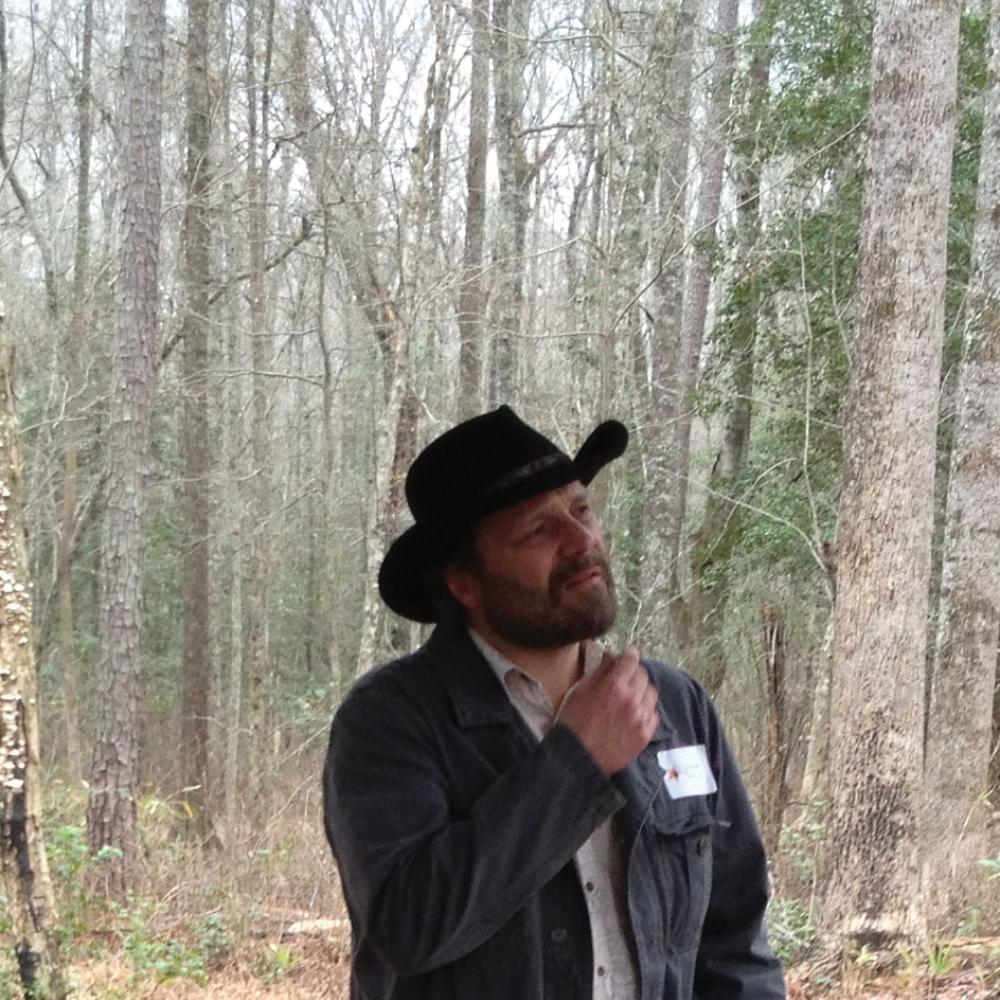 Color photo portrait of Daniel Sayers wearing a black cowboy hat and jacket.