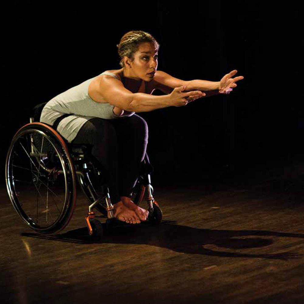 Dancer Alice Sheppard performs onstage with arms outstretched. 
