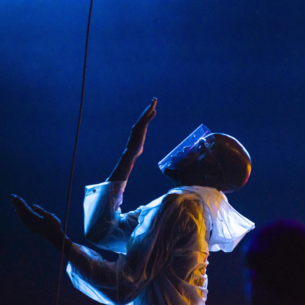 a profile picture of a torso of a male dancer performing in protective gear and face shield.