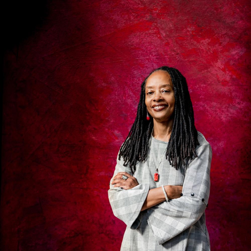 Portrait of Valerie Boyd standing against red background with arms crossed