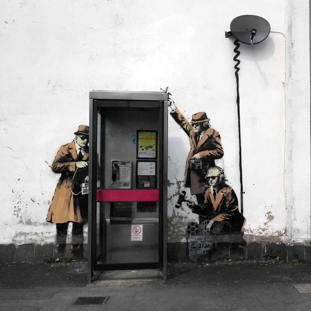 mural of spies tapping into a real phone booth in England